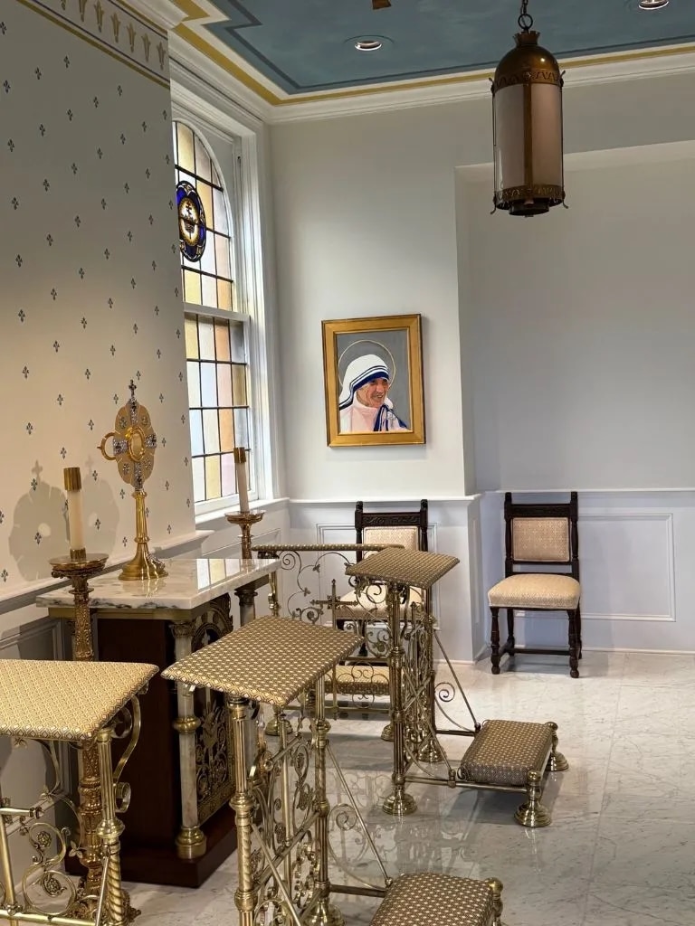 A chapel with kneelers facing the Eucharist in a monstrance, with a painting of a woman on the side wall